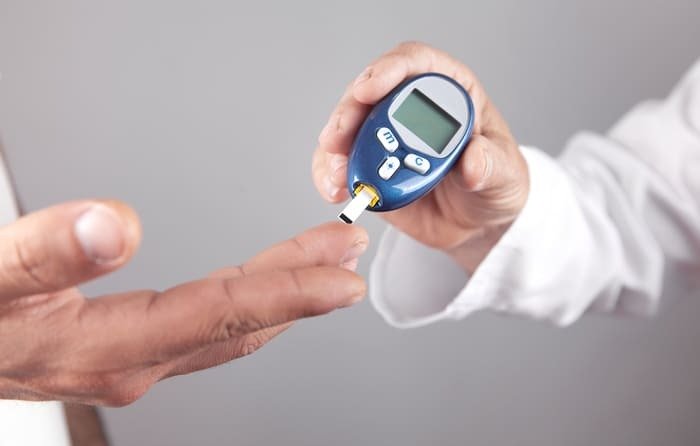 Médico ajuda paciente a medir a glicose.