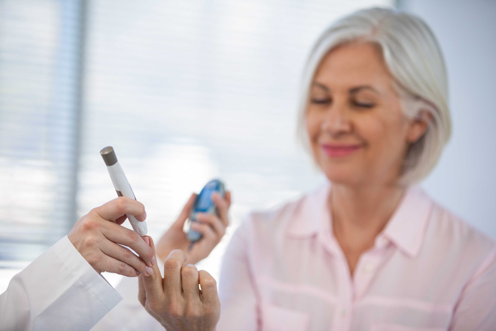 Paciente idosa verifica o nível de glicose no sangue com a ajuda de um médico endocrinologista.