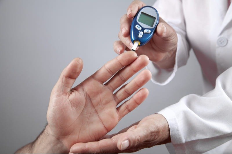 Médico realizando medição glicêmica, essencial para o controle do diabetes.