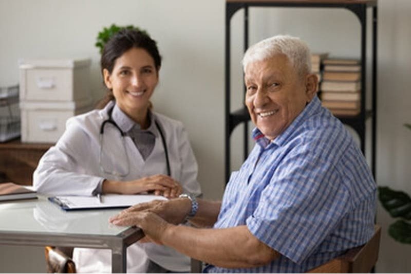 Paciente idoso satisfeito com o seu médico no consultório.